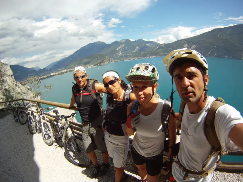 Due ciclisti sorridenti con il casco davanti al lago di Garda