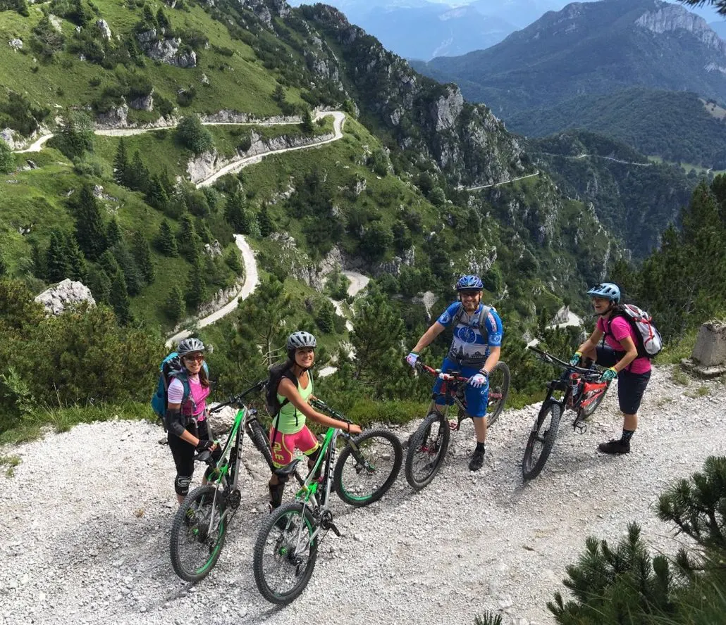 Quattro biker su uno sterrato di montagna con i tornanti alle spalle